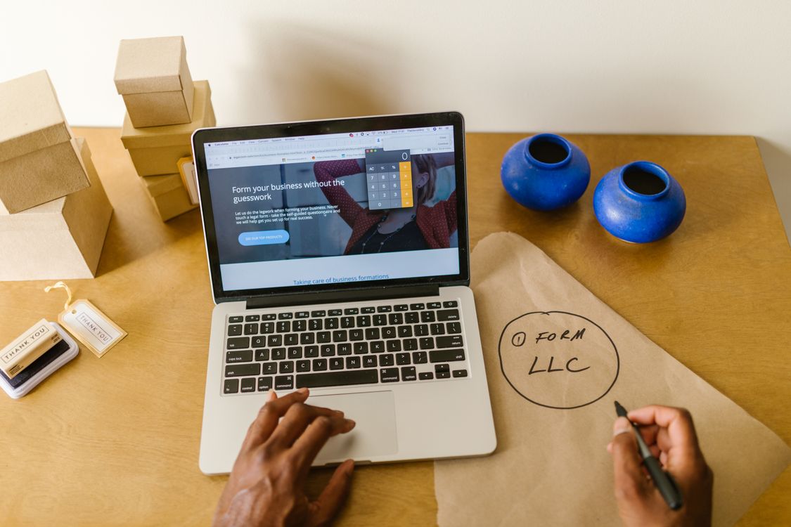 Pessoa iniciando negócio online com laptop e caixas de embalagem