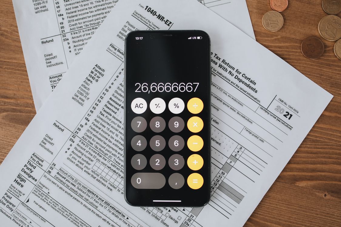 Formulários fiscais e calculadora sobre mesa de madeira, representando o cálculo de impostos de pequenas empresas