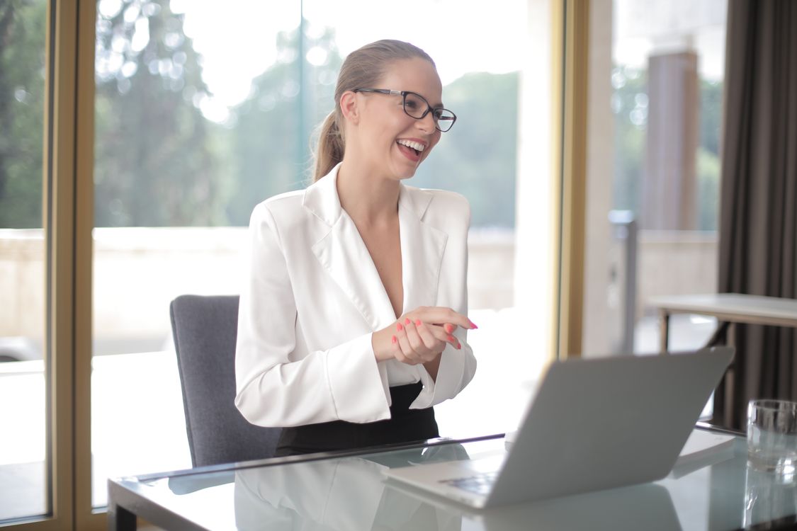 Empreendedora sorridente trabalhando no laptop em escritório moderno