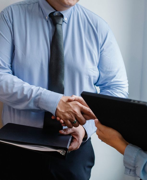 Duas pessoas apertando as mãos em escritório, simbolizando a contratação formal de um funcionário