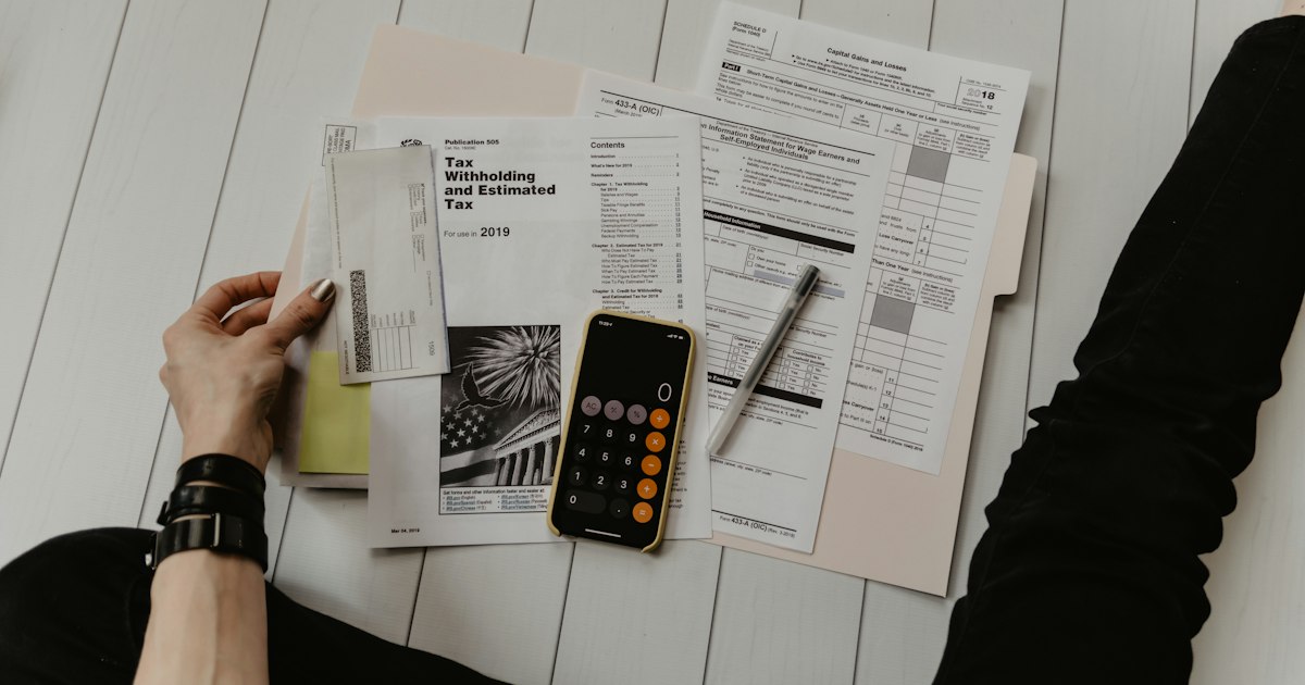 Mesa de trabalho com calculadora, documentos financeiros e laptop para contabilidade